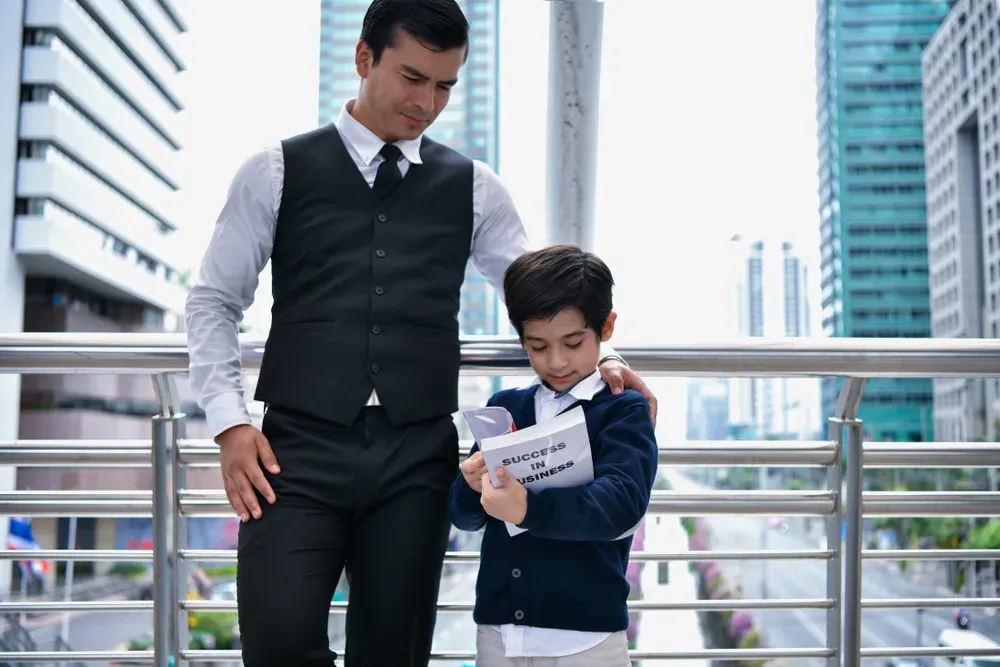 Business concept. Father and son are reading. Dad is teaching business to his son.